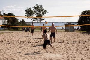 Kompisar spelar volleyboll på stranden i sanden vid havet på TanumStrand på Västkusten