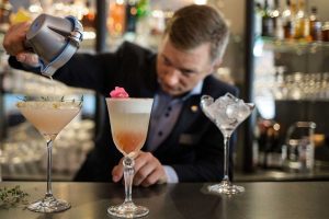Bartender blandar cocktails i lobbybaren på TanumStrand