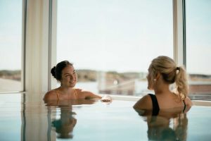 Två kvinnor pratar i relaxpoolen på spa vid havet